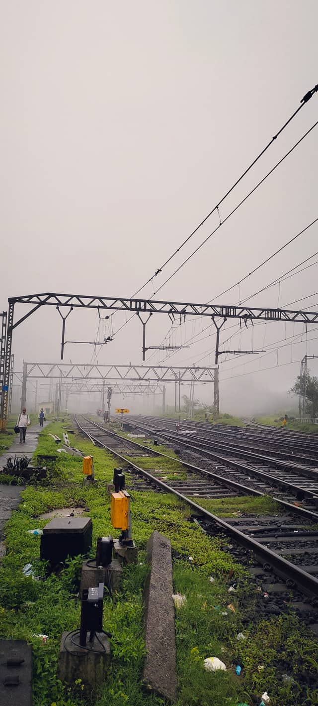 Foggy railway yard with wet tracks fading into mist.