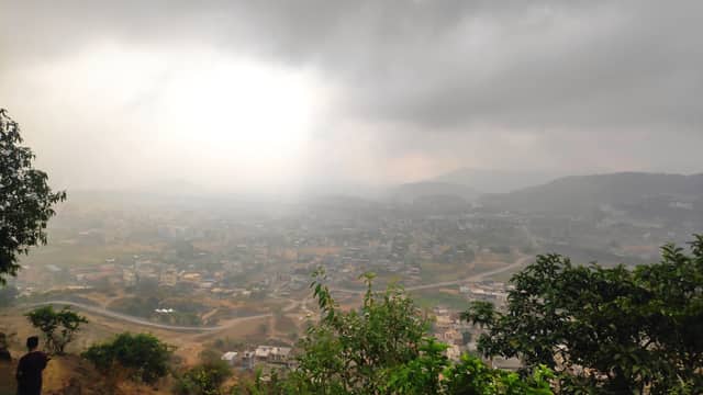Rain clouds hanging over a hillside town view.